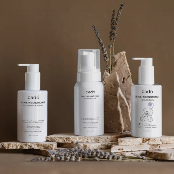 The complete cadó ritual bundle including Leave-in Conditioner, Curl Defining Foam, and the 'For Little Curls' edition on a stone display.