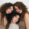 Three women with diverse curly hair types showcasing the results of the complete cadó haircare ritual.
