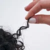 Close-up of a hand holding a perfectly defined and bouncy curl to demonstrate hair elasticity after using cadó styling products.
