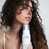 Model holding cadó Curl Defining Foam showcasing voluminous and bouncy curls with professional hold.