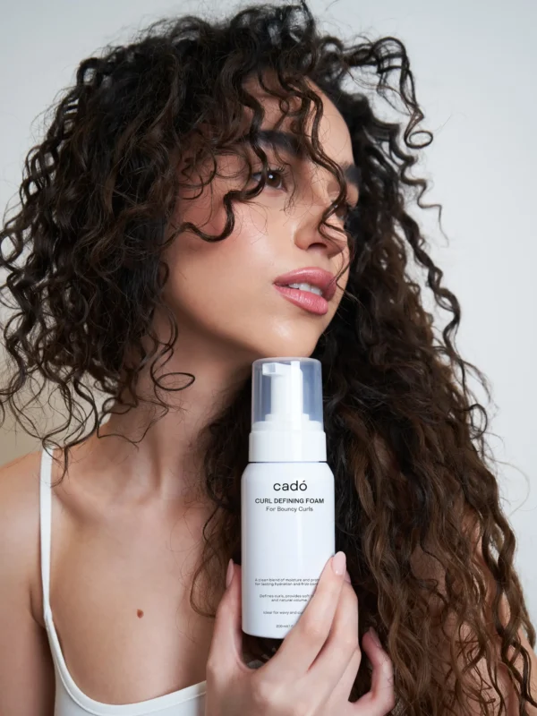 Model holding cadó Curl Defining Foam showcasing voluminous and bouncy curls with professional hold.