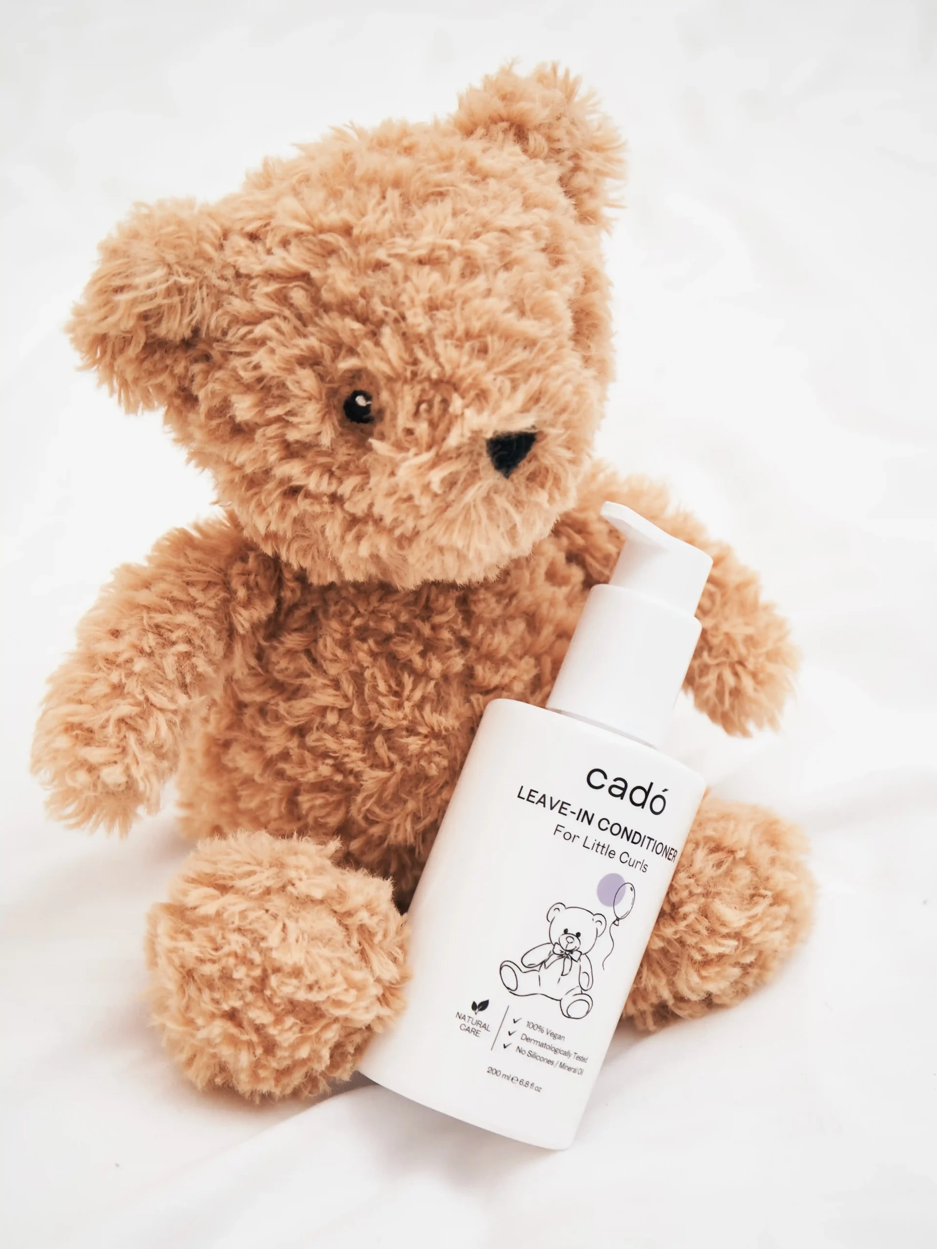 Gentle leave-in conditioner for kids with curly hair, featuring the cadó 'For Little Curls' bottle next to a teddy bear.