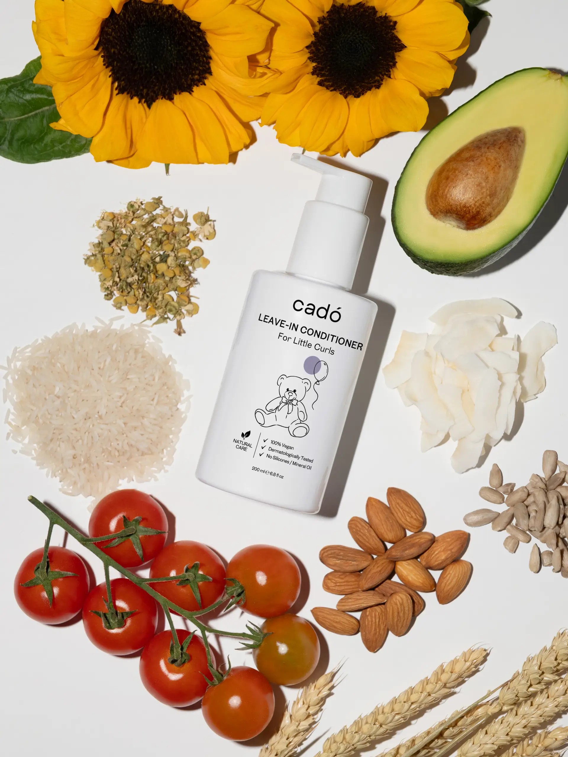 Natural ingredients for kids' curly hair products including avocado, sunflower, and almonds, surrounding the cadó 'For Little Curls' conditioner.