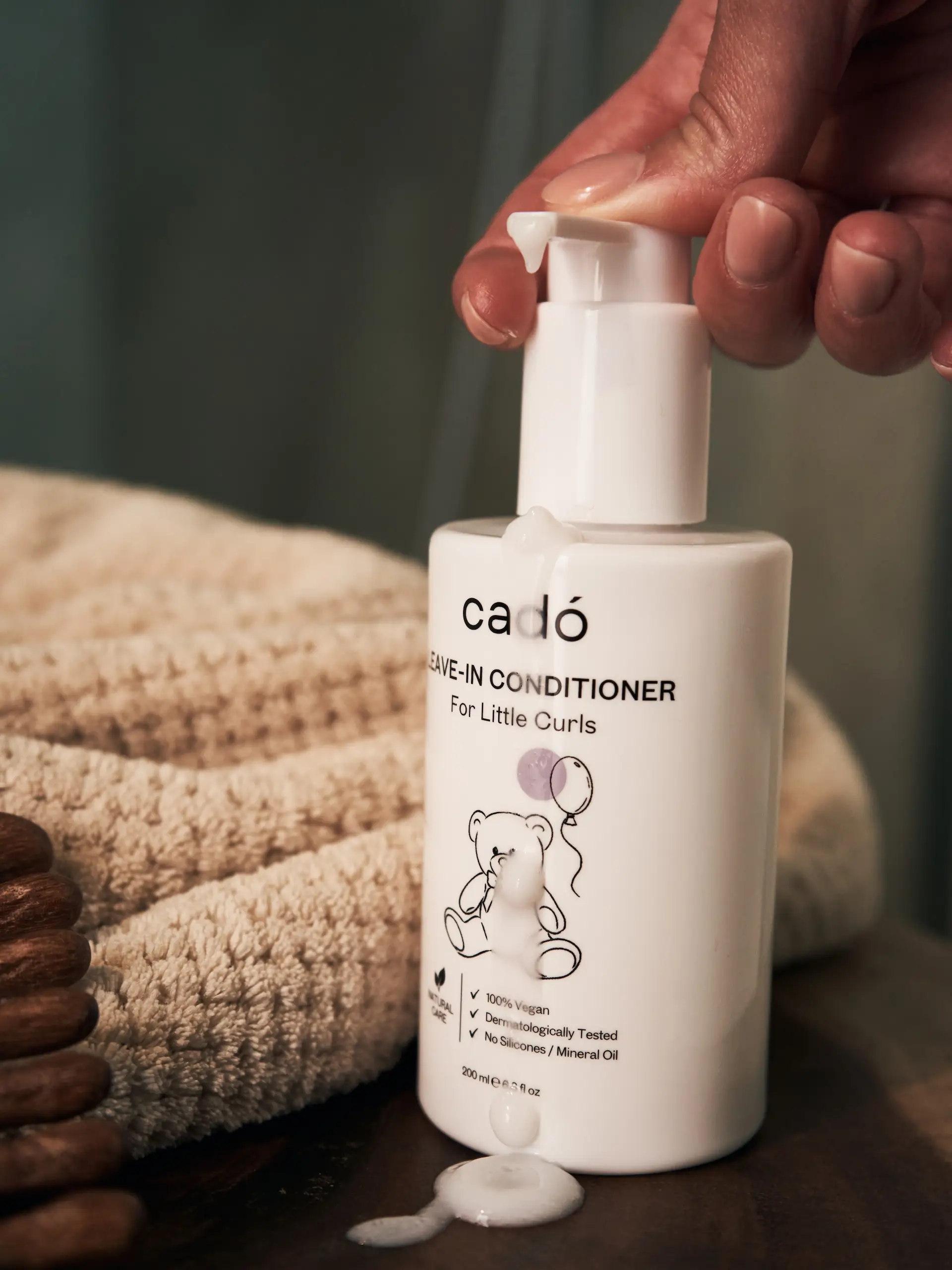 Gentle creamy texture of cadó For Little Curls Leave-in Conditioner being dispensed for easy detangling and hydration.