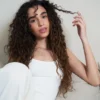 Lifestyle portrait of a woman with long, shiny and defined curls achieved with cadó professional hair products.