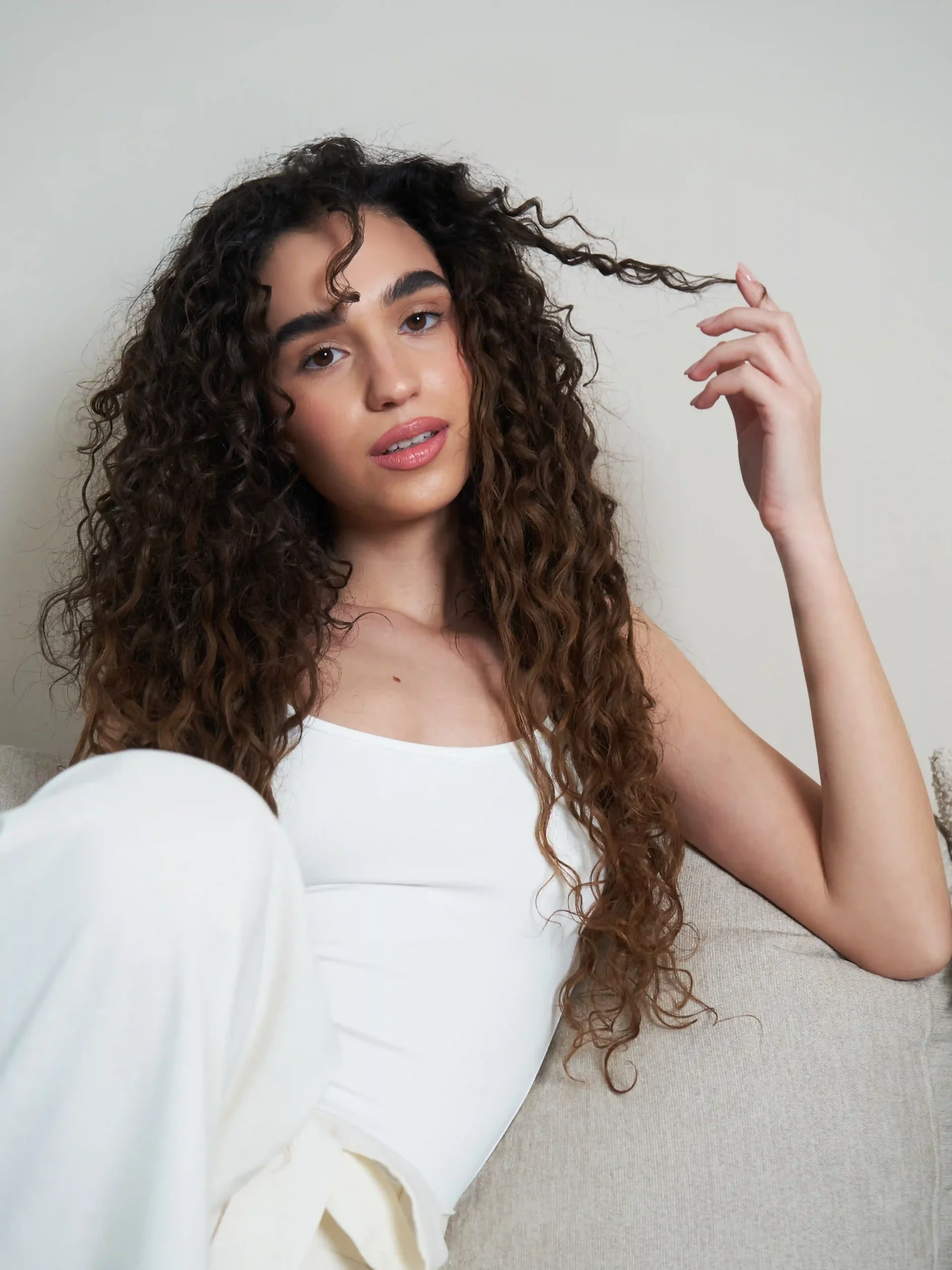 Lifestyle portrait of a woman with long, shiny and defined curls achieved with cadó professional hair products.
