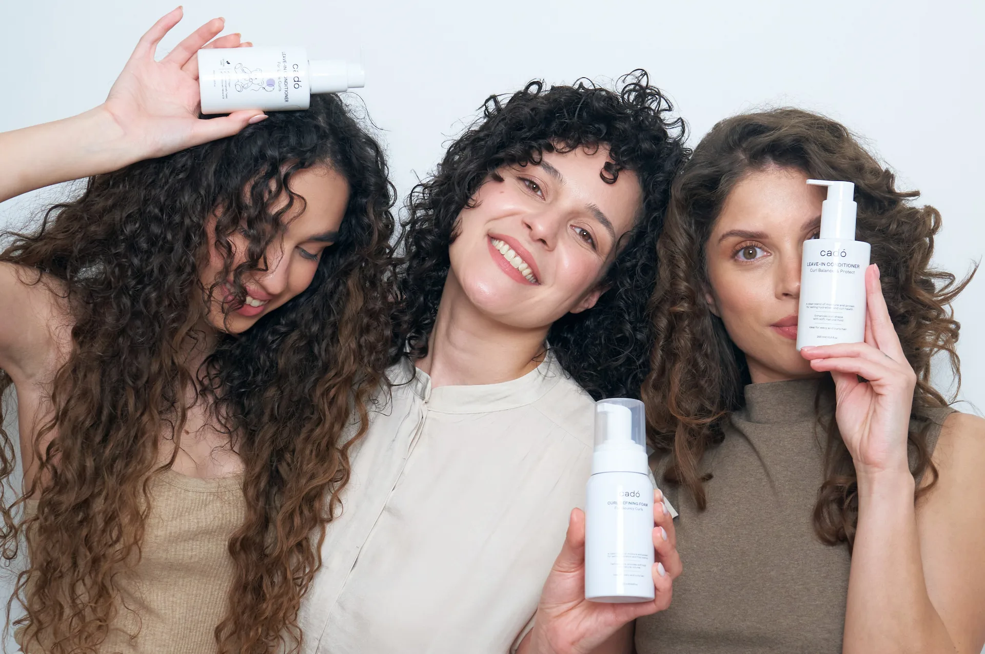 Diverse group of women smiling and showcasing their healthy, defined curls after using the cadó professional ritual.